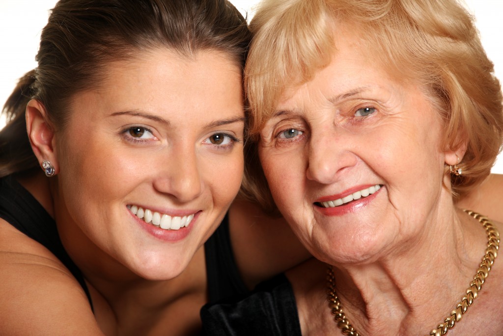 A young woman and an elderly woman smiling closely together.